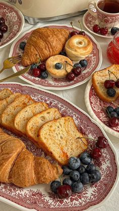 croissants, blueberries and coffee are served on red plates with floral designs