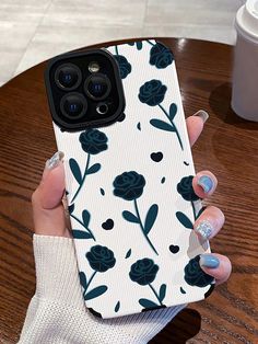 a woman is holding up her phone case with flowers on it and blue nail polish