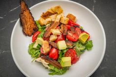 a white plate topped with salad and french toast on top of a black countertop