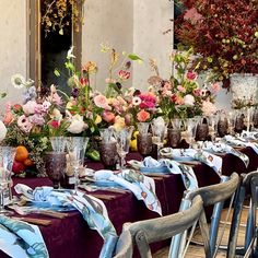 a long table with many vases filled with flowers and napkins on top of it