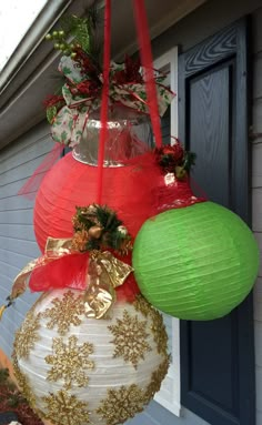 christmas decorations hanging from the side of a house on a front porch with red and green paper lanterns