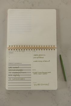 a notepad with writing on it next to a green pen and a spiral - bound notebook