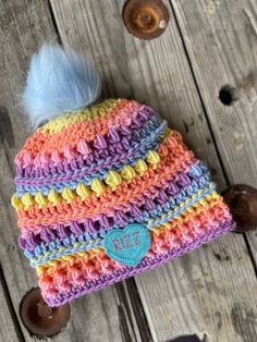 a multicolored crocheted hat with a blue pom - pom