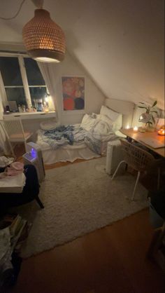 a bedroom with a bed, desk and window in the corner is lit by candles