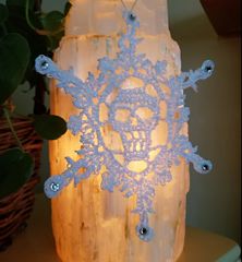 a lighted snowflake sitting on top of a table next to a potted plant