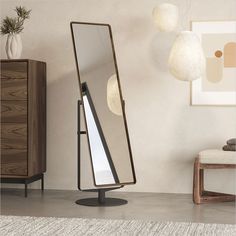 a large mirror sitting on top of a metal stand in front of a wall mounted light