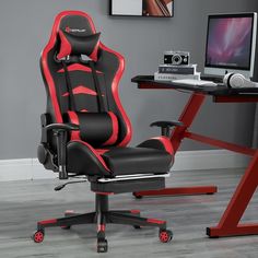 an office chair with red and black trim sits in front of a computer desk