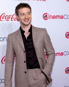 a man in a suit standing on a red carpet