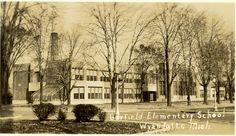 an old black and white photo of a school building with trees in the foreground