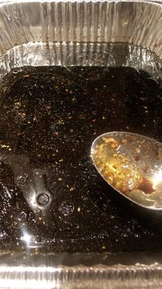 a spoon with food in it sitting on top of a metal pan filled with liquid