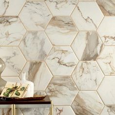 a white marble tile wall with hexagonal tiles in the background and a vase on a table