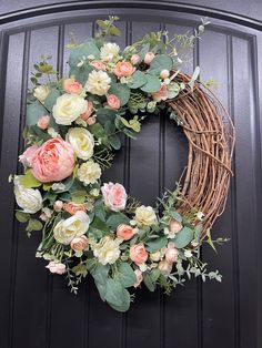 a wreath with pink and white flowers hanging on a door