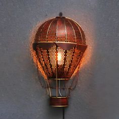 a light that is on the wall next to a gray wall with a birdcage in it