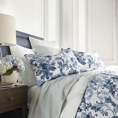 a bed with blue and white comforters in a bedroom next to a night stand