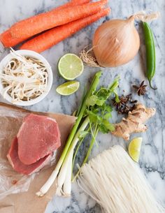 raw meat and vegetables on a marble counter top