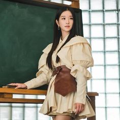 a woman in a dress standing next to a chalkboard with her hands on her hips