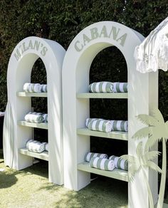 there are many white shelves that have towels on them in front of the bushes and trees