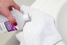 a person is using a bottle of deodorant to clean a white towel