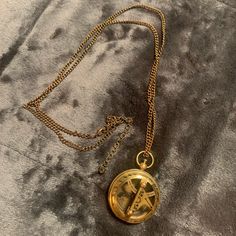 a gold necklace with a compass on it