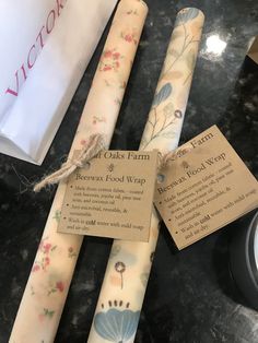 three rolls of beeswax food wrap sitting on a table next to a clock