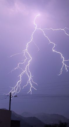 a lightning bolt is seen in the sky above power lines