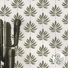 a cactus is standing in front of a wall with green leaves on it