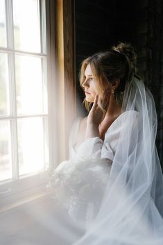 a woman sitting in front of a window wearing a veil