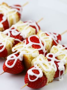 strawberry shortcakes with white icing and strawberries on them sitting on a plate