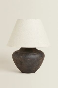 a brown vase with a white shade on it's side and a light in the middle