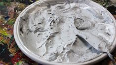 a white bowl filled with lots of white stuff on top of a table covered in paint