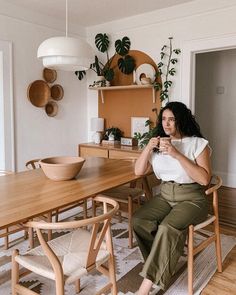 a woman sitting at a table drinking coffee