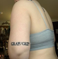 a woman with a tattoo on her arm that says gray / gry in black