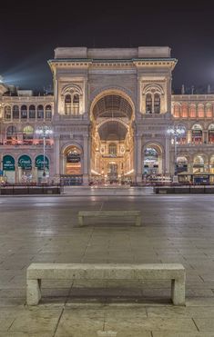 an empty bench in front of a building at night