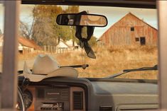 there is a cowboy hat on the dashboard of a car in front of an old barn