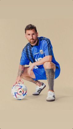 a man kneeling down with a soccer ball in front of his face and hands on his knees