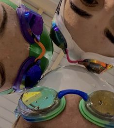 two people wearing goggles and masks with different colored frames on their faces, one man has his eyes closed while the other wears sunglasses