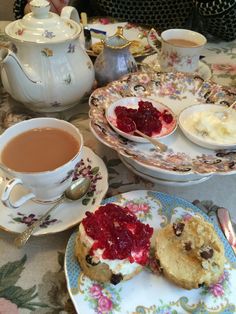 a table topped with tea cups and plates filled with desserts on top of it