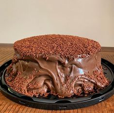 a cake with chocolate frosting and sprinkles sitting on top of a black plate