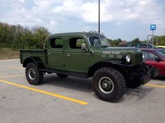 an old green truck parked in a parking lot