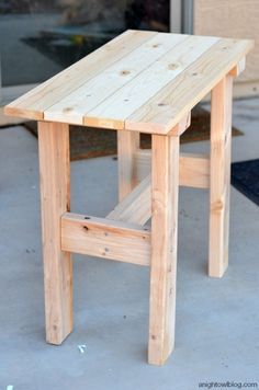 a small wooden table sitting on top of a cement floor next to a garage door