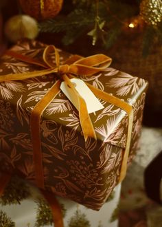 a gift wrapped in brown and gold paper with a bow on it's side