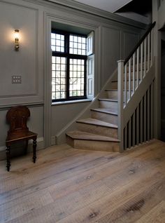 an empty room with stairs and a chair next to the window on the far wall