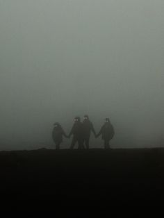 three people walking in the fog holding hands