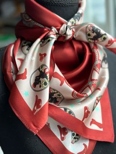 a red and white scarf with cats on it is sitting on a mannequin