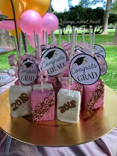 cake pops with pink and white frosting on a gold platter at a graduation party