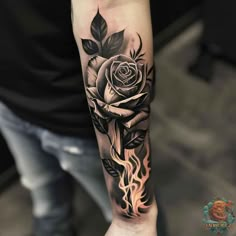 a black and white rose tattoo on the left arm with flames coming out of it