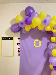 a purple and yellow door with balloons on the front, and an arch in the back