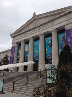 an old building with columns and banners on the front wall, along with steps leading up to it