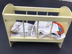 a wooden toy crib with clothes in it