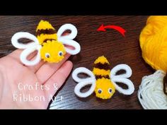 two crocheted bees sitting on top of a wooden table next to yarn balls